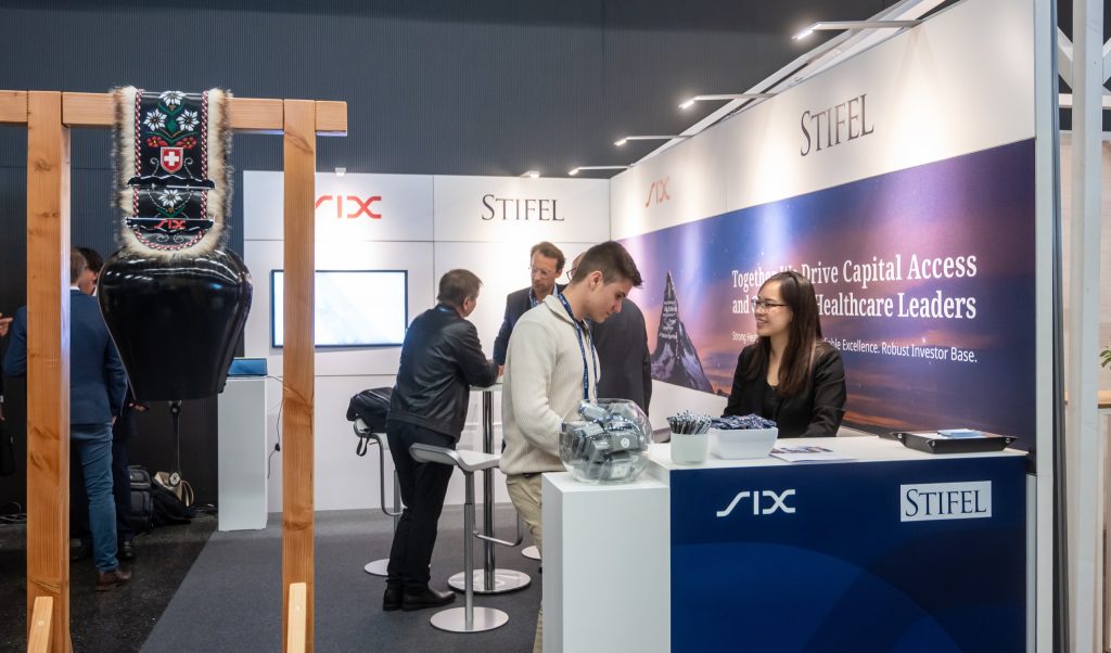 Stifel's mentoring booth at the Swiss Biotech Day 2026, shared with SIX, a delegate in conversation at the counter