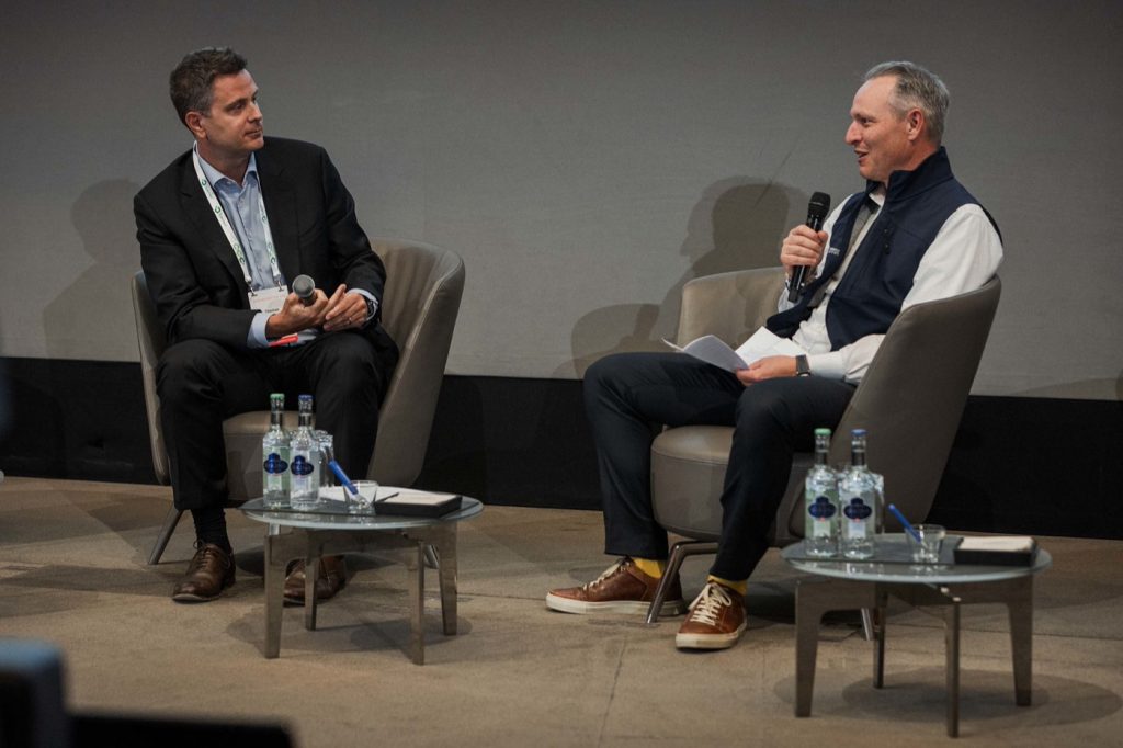 Two speakers in armchairs on the plenary stage during the fireside session