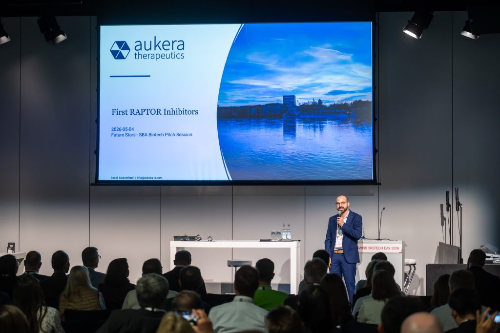 Pitch session speaker standing on stage in front of a start-up's title slide